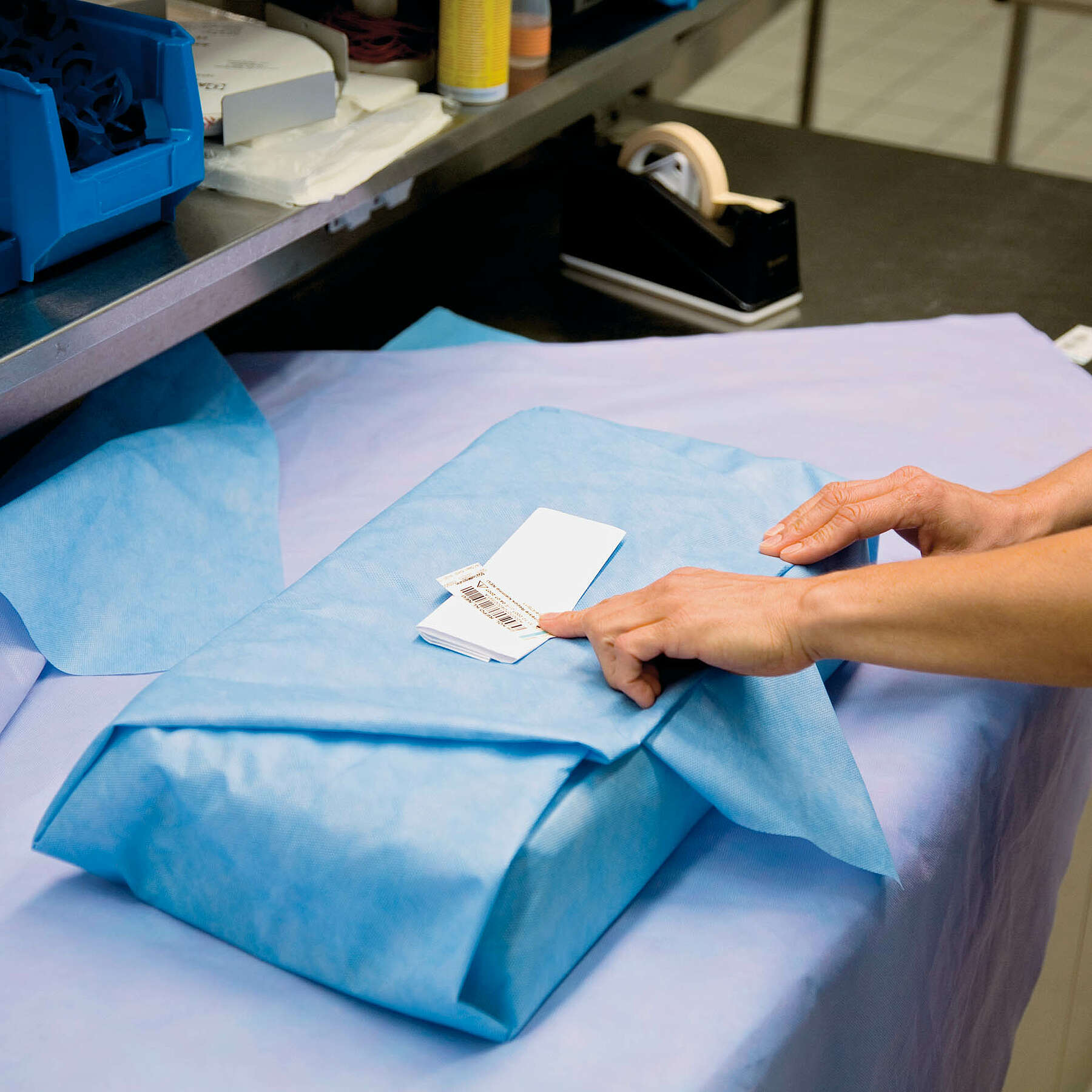 Das Verbundsieb mit den chirurgischen Instrumenten wird in medizinisches Vlies verpackt. Das Verbundsieb mit den chirurgischen Instrumenten wird in medizinisches Vlies verpackt.